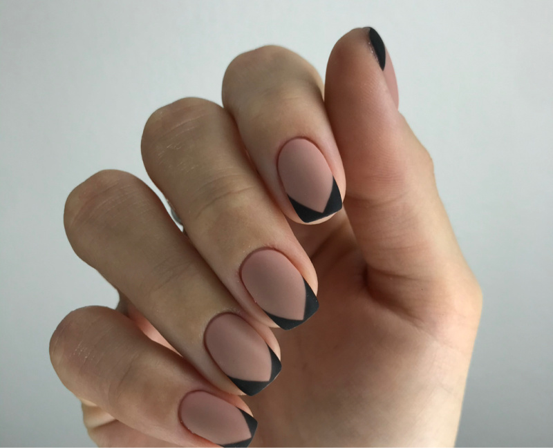 Close-up of a manicure with soft nude tones and black tips